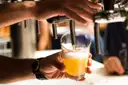 A hand pouring a pale beer from a bar tap