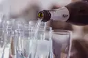 Prosecco being poured into a row of glasses