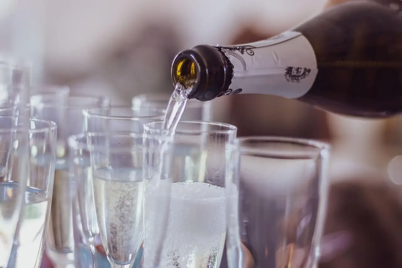 Prosecco being poured into a row of glasses