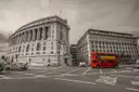 A red double-decker bus at a London junction, picked out in colour against black and white
