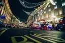 Christmas lights over Regent Street at night with red buses below