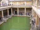 The green waters of the Great Bath at the Roman Baths, ringed by columns and statues