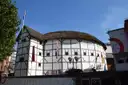Shakespeare's Globe, the white timber-framed thatched theatre on Bankside, under a blue sky