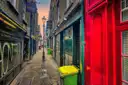 A narrow paved alley in the East End with an old street lamp and shop fronts