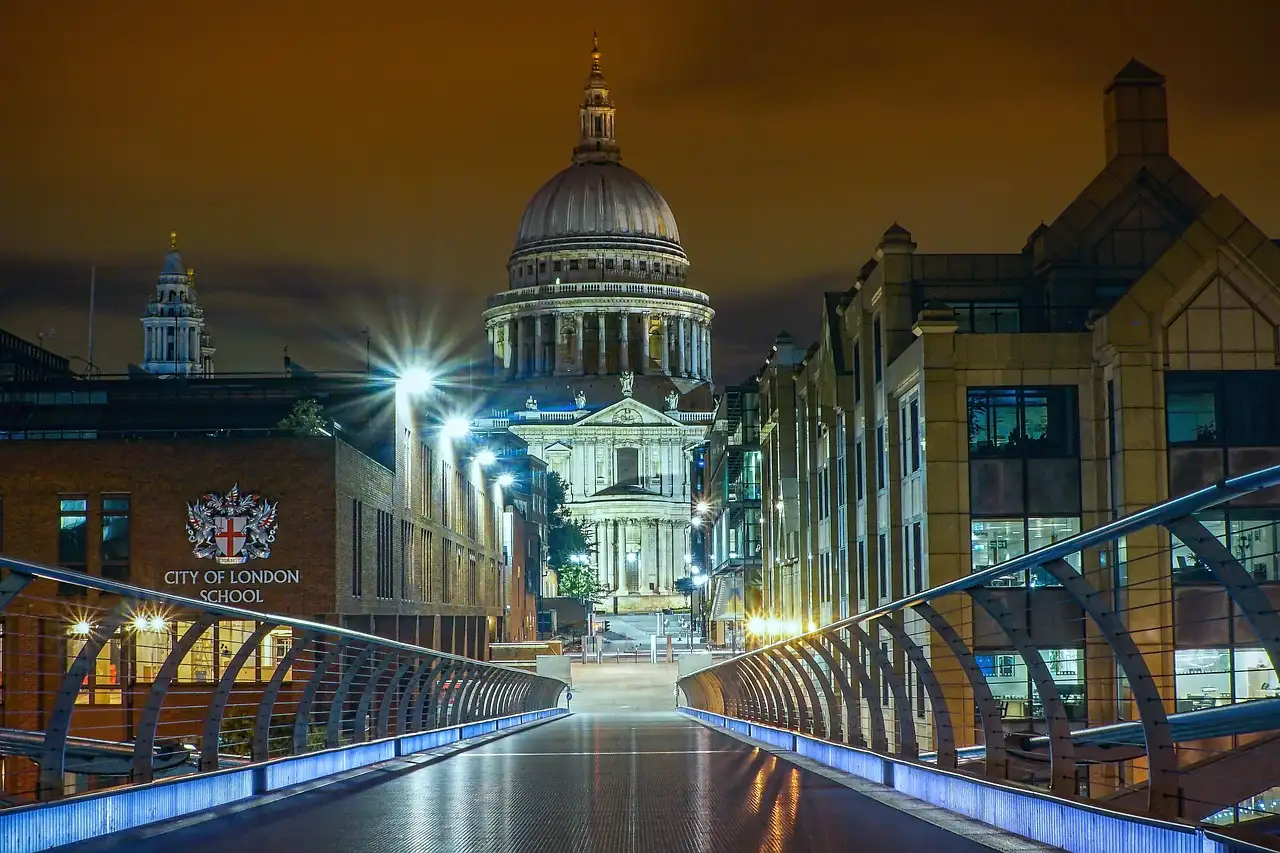 St Paul's Cathedral dome lit at night at the end of a bridge walkway