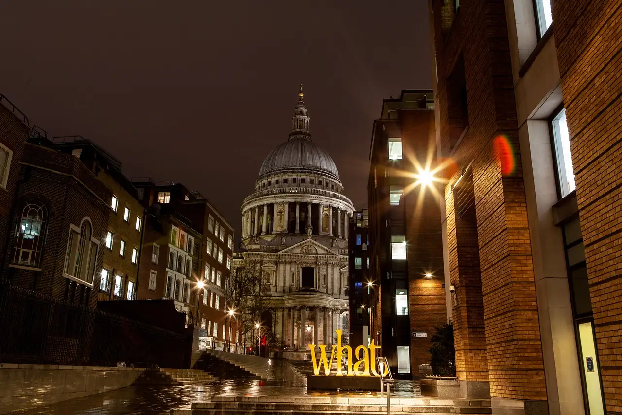 St Paul's Cathedral lit up at night at the end of a dark lane in the City of London