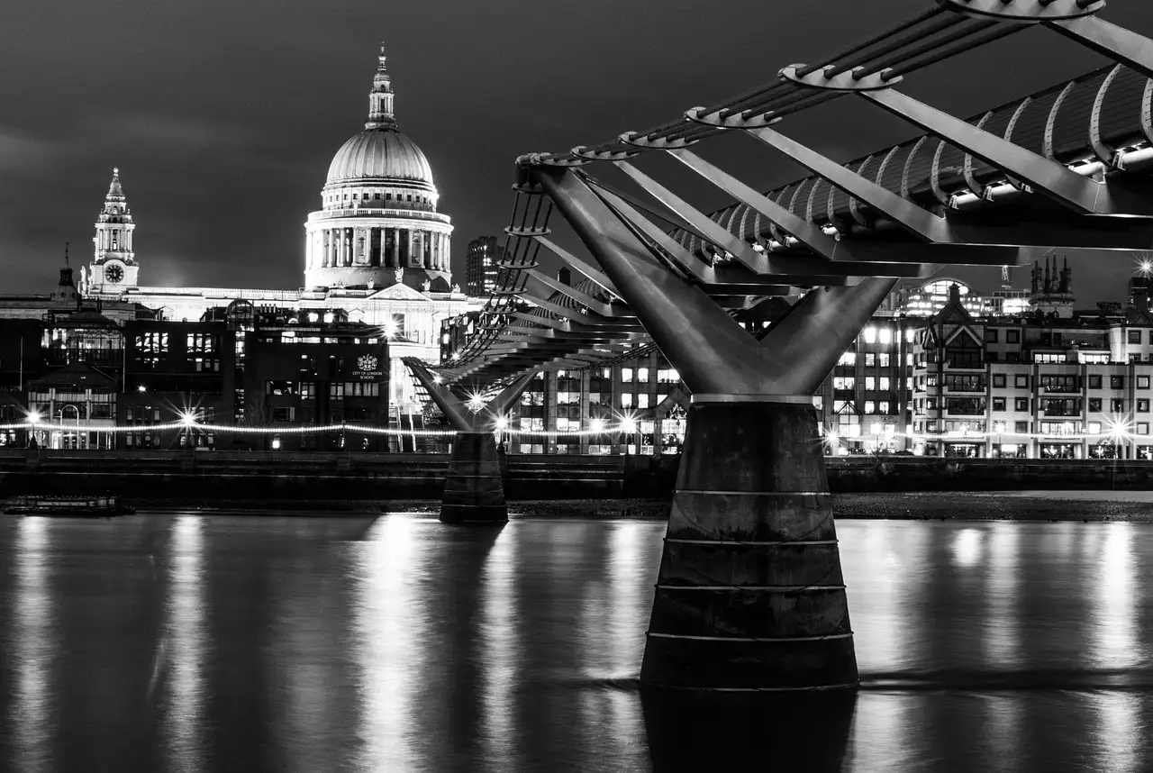 Black-and-white night view of St Paul's Cathedral beyond the Millennium Bridge