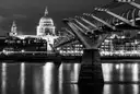 Black-and-white night view of St Paul's Cathedral beyond the Millennium Bridge
