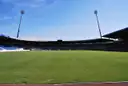 A football pitch with floodlight towers under a clear blue sky