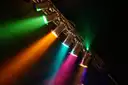 A row of stage spotlights throwing coloured beams