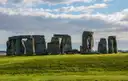 Stonehenge on the green grass of Salisbury Plain under a sky of white clouds
