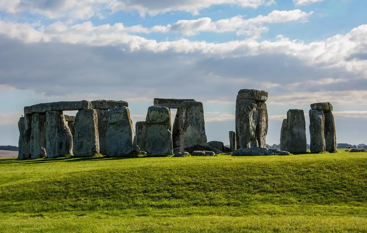 Stonehenge on the green grass of Salisbury Plain under a sky of white clouds