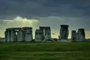Stonehenge under a dark sky with sunbeams breaking through the clouds