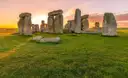 Stonehenge standing stones on green grass at sunset