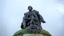 Bronze statue of a seated William Shakespeare against a cloudy sky