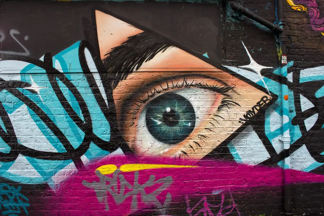 A large painted eye among graffiti tags on an East London wall