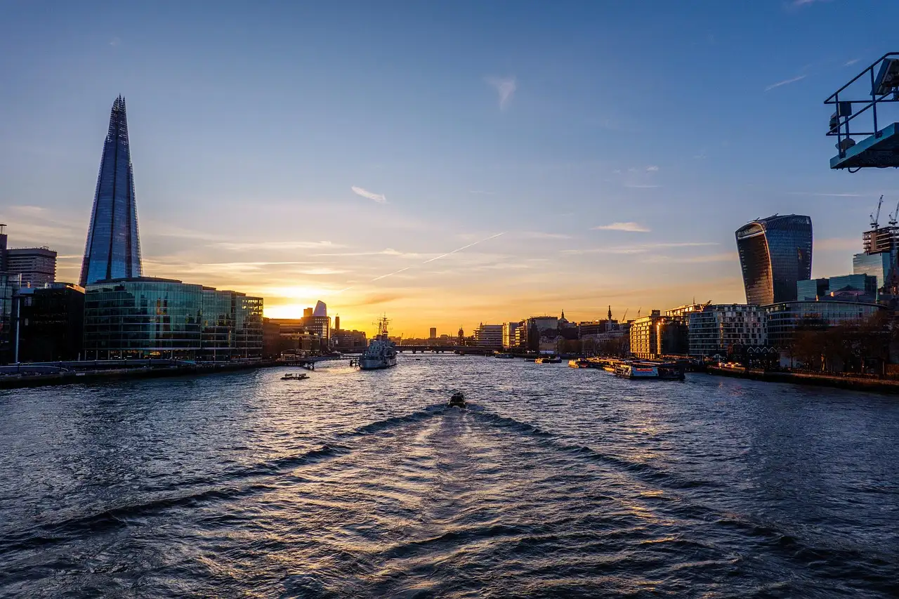 View from a boat on the River Thames towards the Shard at sunset, with the boat's wake in the water