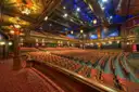 A grand theatre auditorium with tiers of seats under an ornate lit ceiling