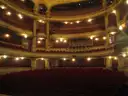 Theatre balconies lined with lamps above rows of red seats