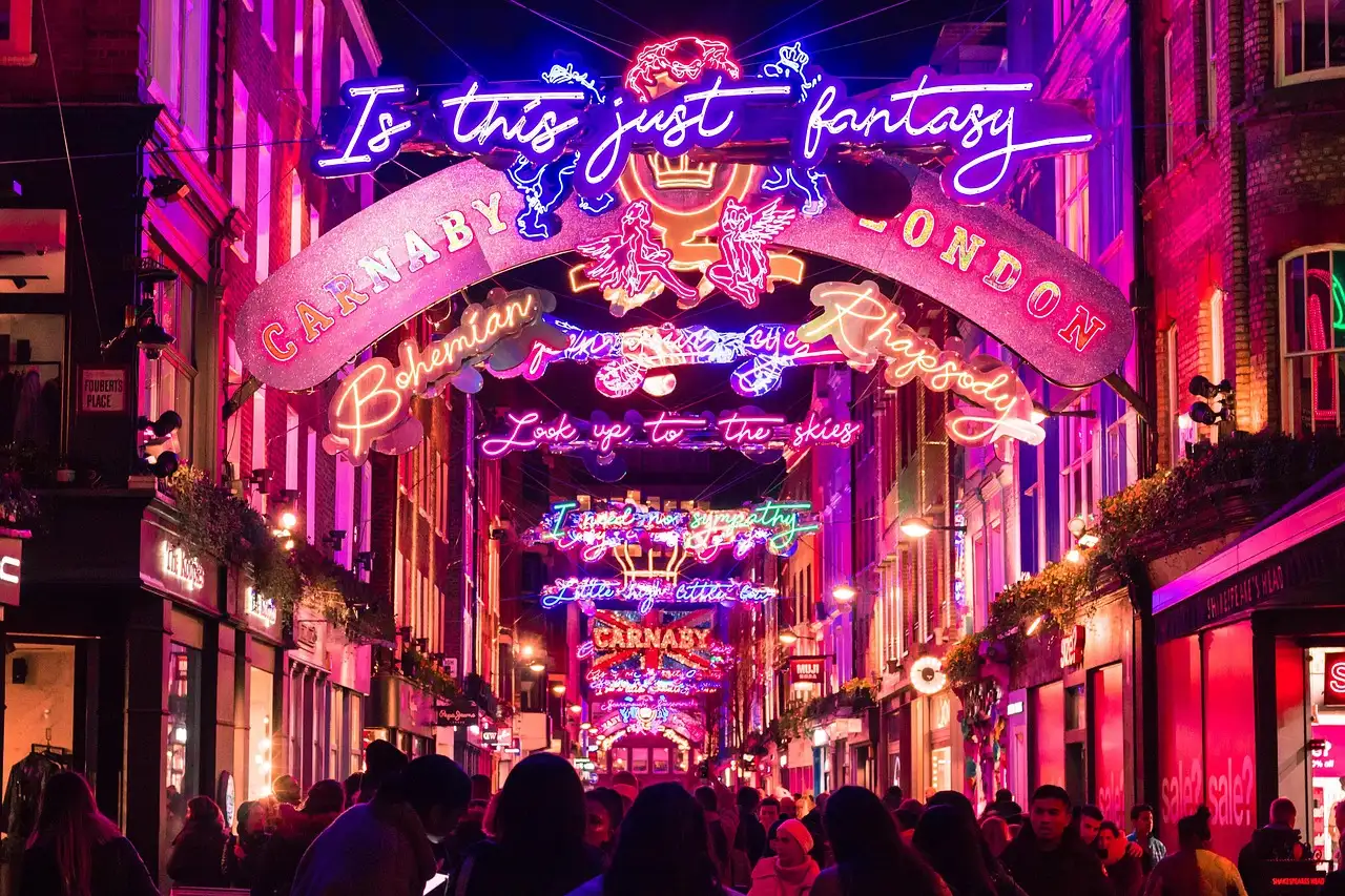 A crowded London street arched over with pink and blue neon Christmas lights