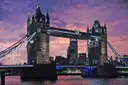 Tower Bridge lit against a purple and pink sunset sky, reflected in the Thames