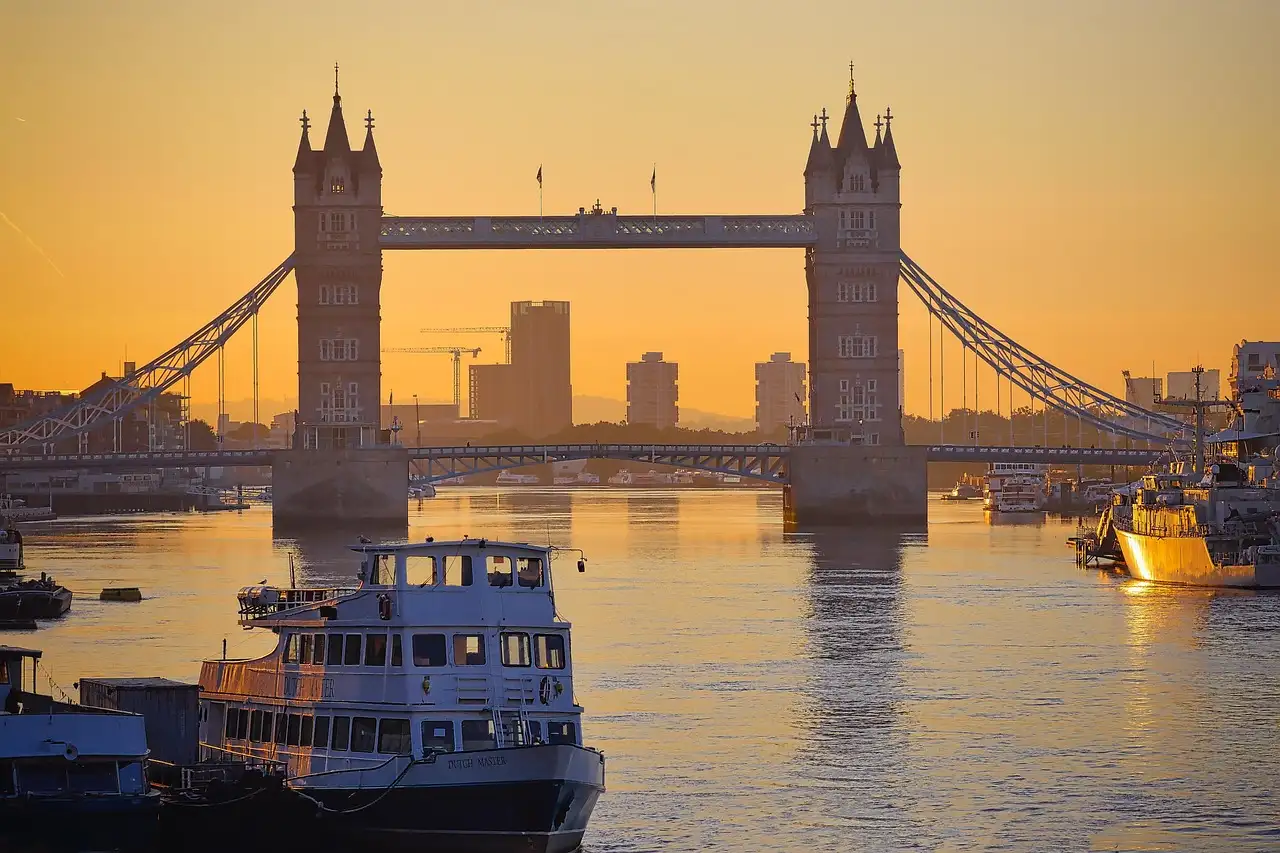 Tower Bridge at sunrise, with a passenger boat moored on the River Thames