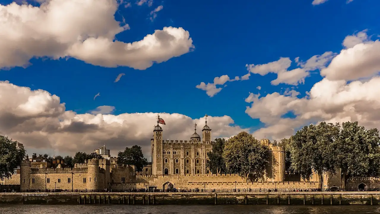 Tower of London on the riverside under a blue sky with large white clouds