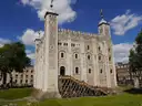 The White Tower inside the Tower of London under a blue sky with white clouds