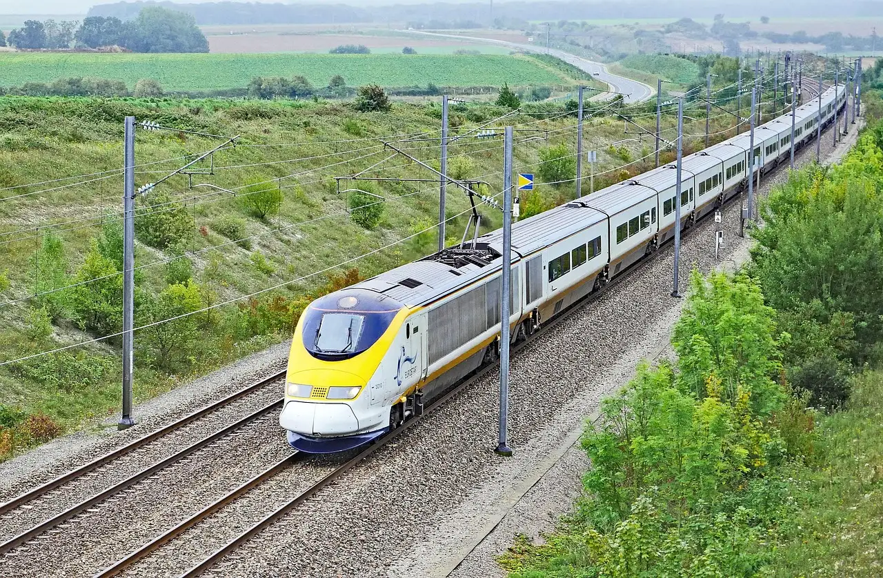 A yellow-nosed Eurostar high-speed train running along a track through green countryside