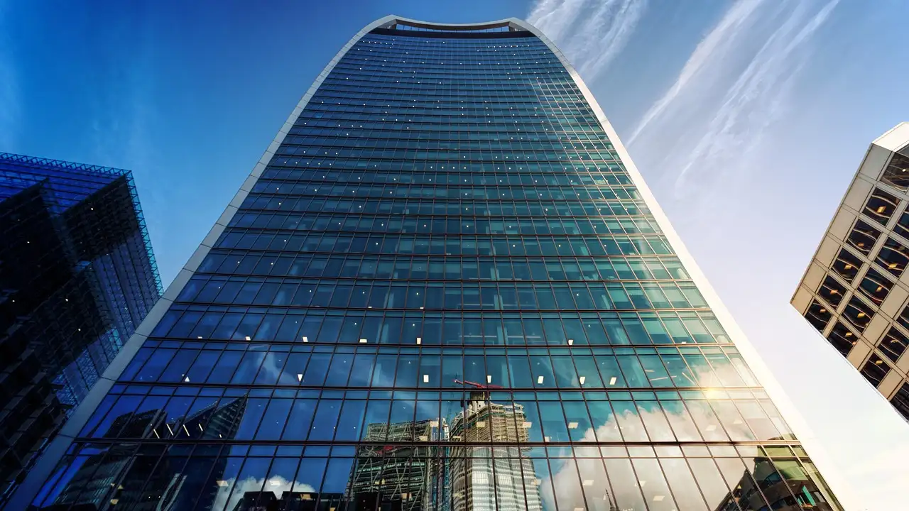 Looking up at the curved glass Walkie-Talkie tower against a blue sky