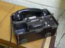 An old military field telephone with its handset resting on top