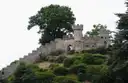 Battlements and towers of Warwick Castle on a tree-covered mound