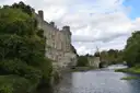 Warwick Castle walls above the River Avon and green trees
