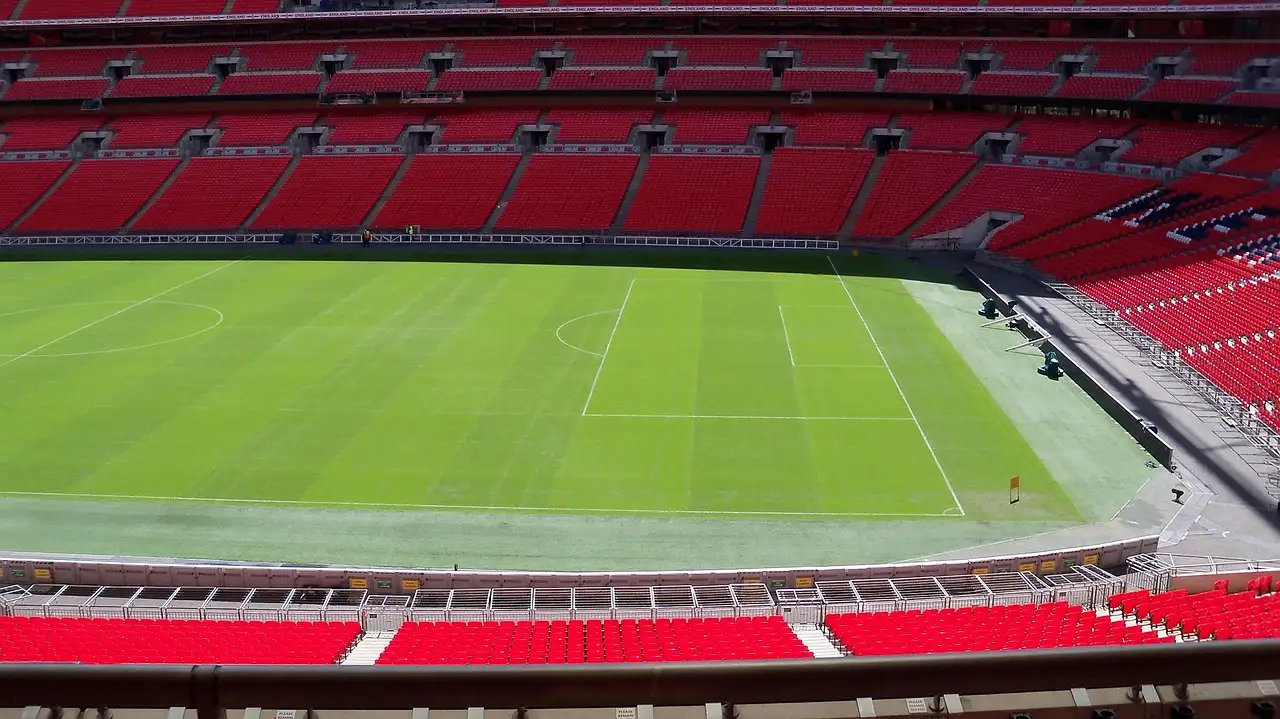Rows of red seats around the empty green pitch of Wembley Stadium