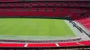 Rows of red seats around the empty green pitch of Wembley Stadium