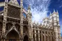 Gothic front and towers of Westminster Abbey under a blue sky with white clouds