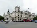 Grand government buildings on Whitehall with red buses passing