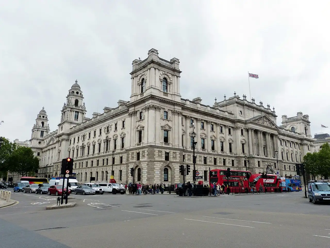 Grand government buildings on Whitehall with red buses passing