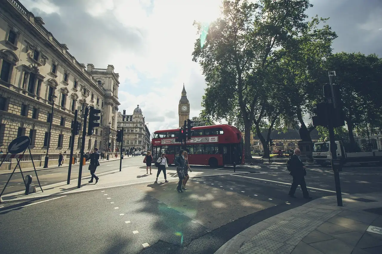 A Westminster street with Big Ben in the distance and a red double-decker bus crossing