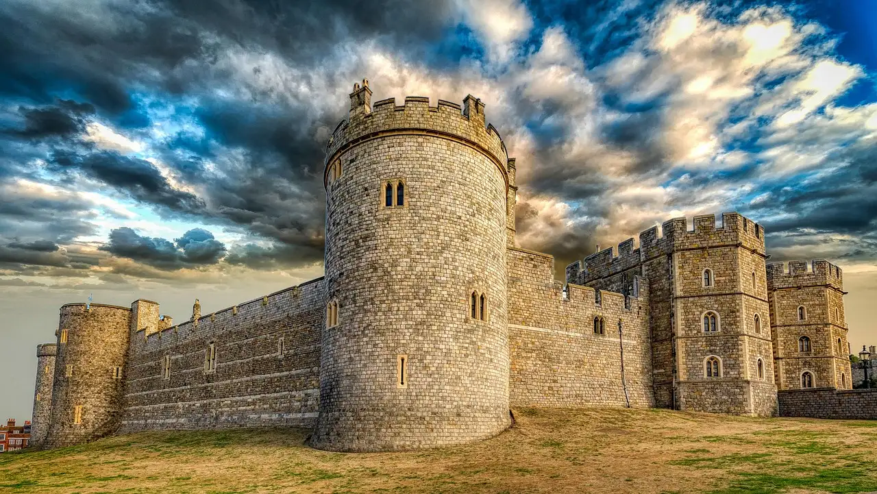The stone walls and towers of Windsor Castle under a dramatic sky