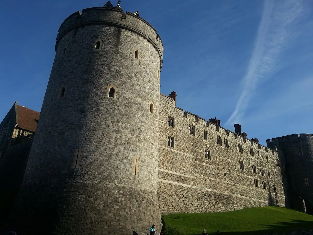 A round tower and the curtain wall of Windsor Castle under a blue sky