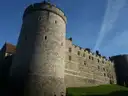 A round tower and the curtain wall of Windsor Castle under a blue sky