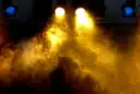 Warm yellow stage lights shining through smoke