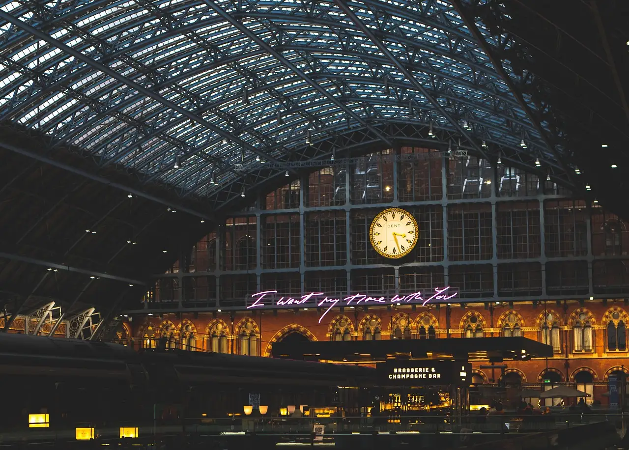 The great arched iron-and-glass roof of St Pancras station lit at night, with a large clock above the concourse