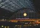 The great arched iron-and-glass roof of St Pancras station lit at night, with a large clock above the concourse